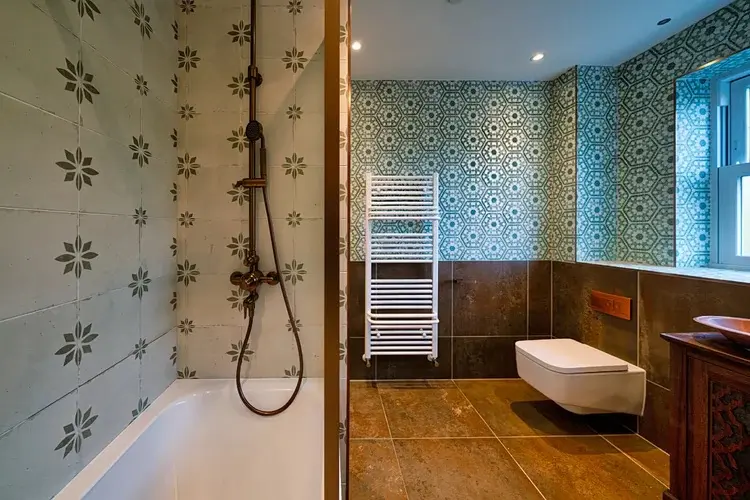 Patterned bathroom with freestanding bath and brass fittings at Ascot