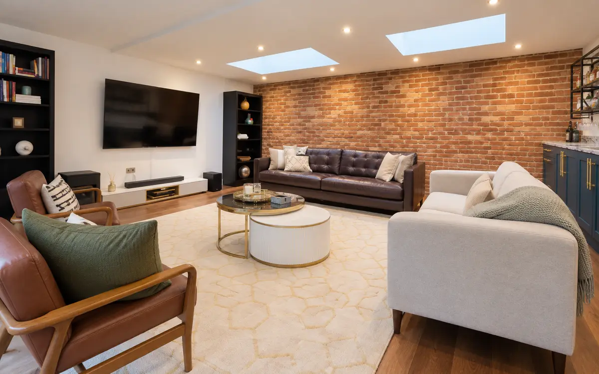 Completed lounge interior with exposed brick wall and rooflights at Ealing Common